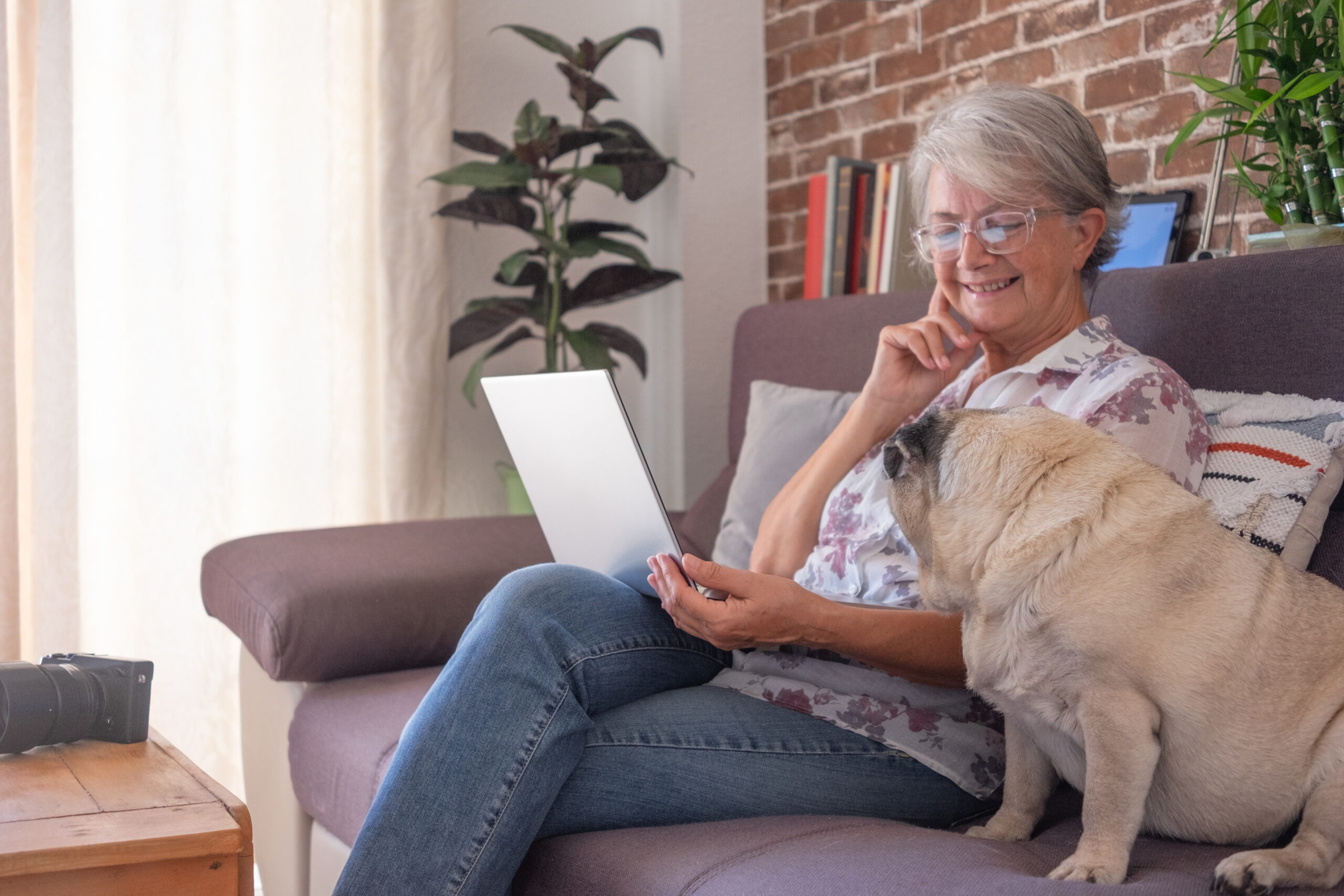 Happy Senior Sitting On Sofa With Dog
